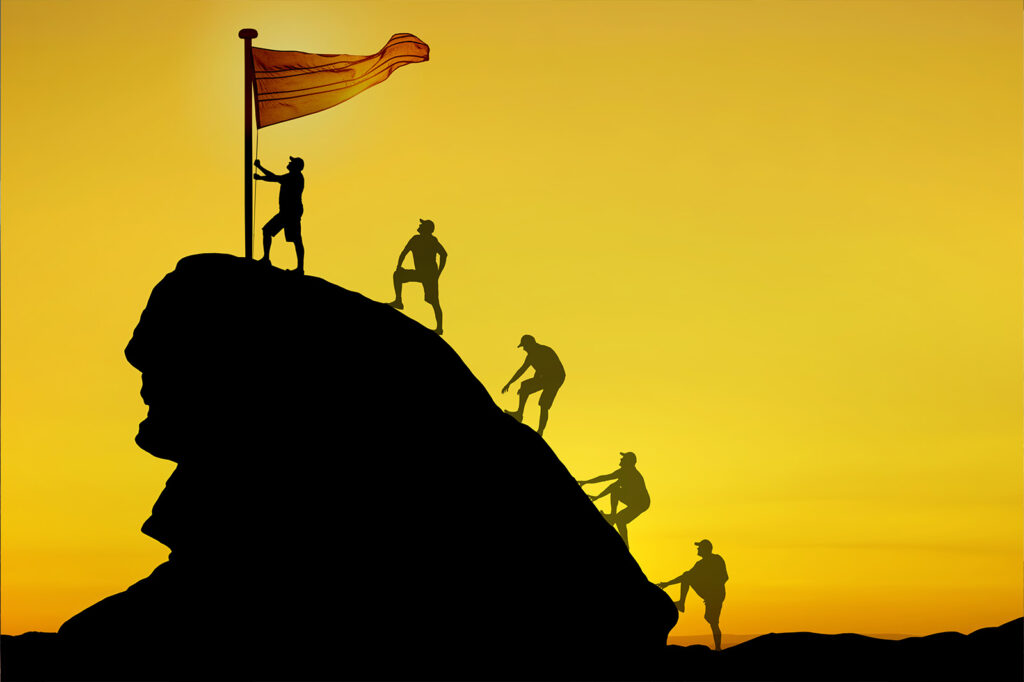 group of leaders planting a flag at the top of a hill.