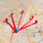 Map with multiple pushpins marking each location with a red string between each pin.